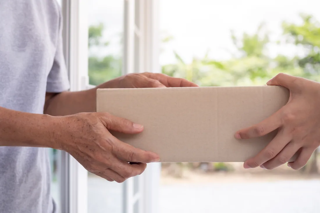 A plain, unbranded parcel being handed to someone at home